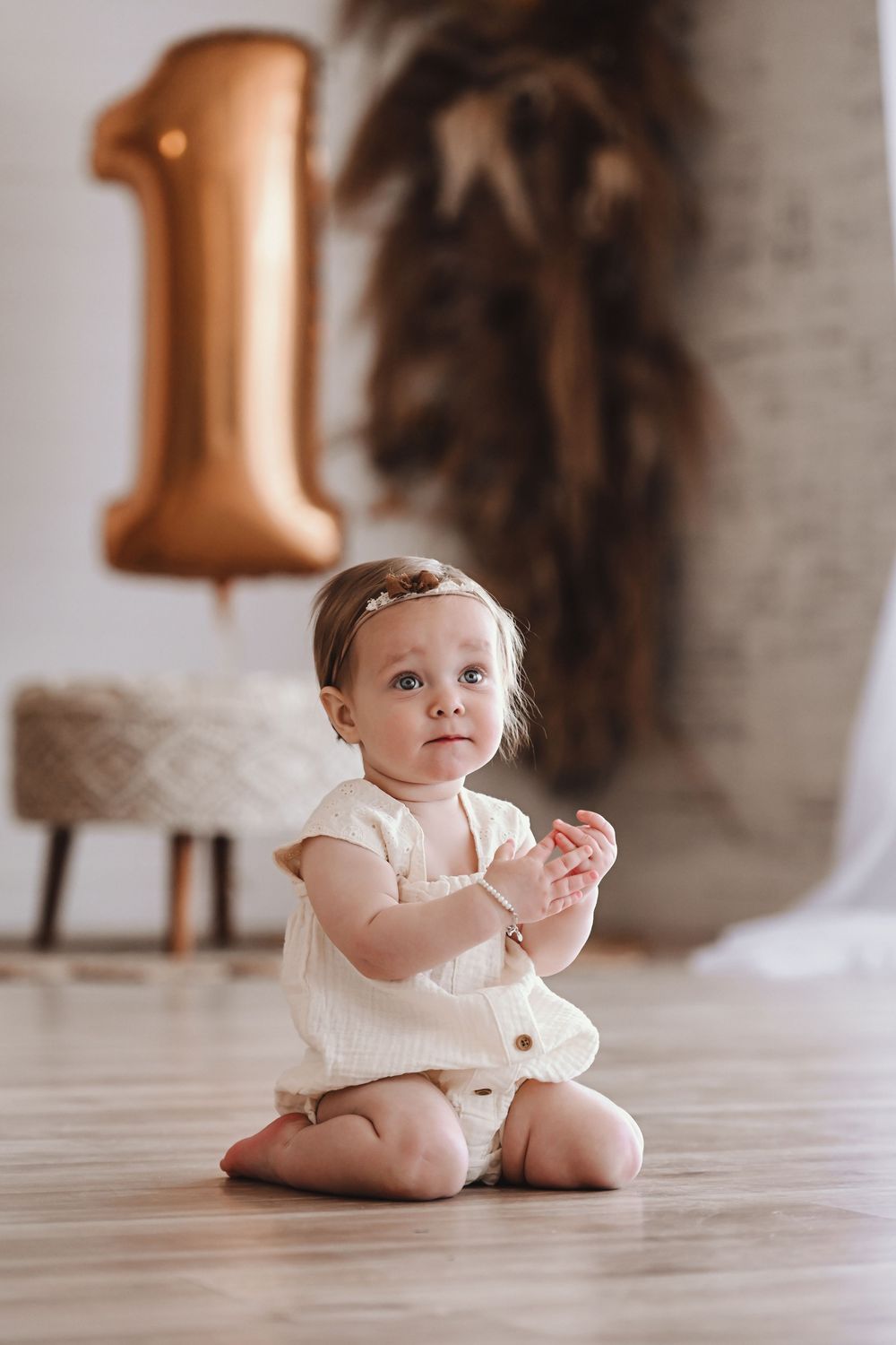 First birthday photoshoot setup with rose gold decorations and neutral tones.