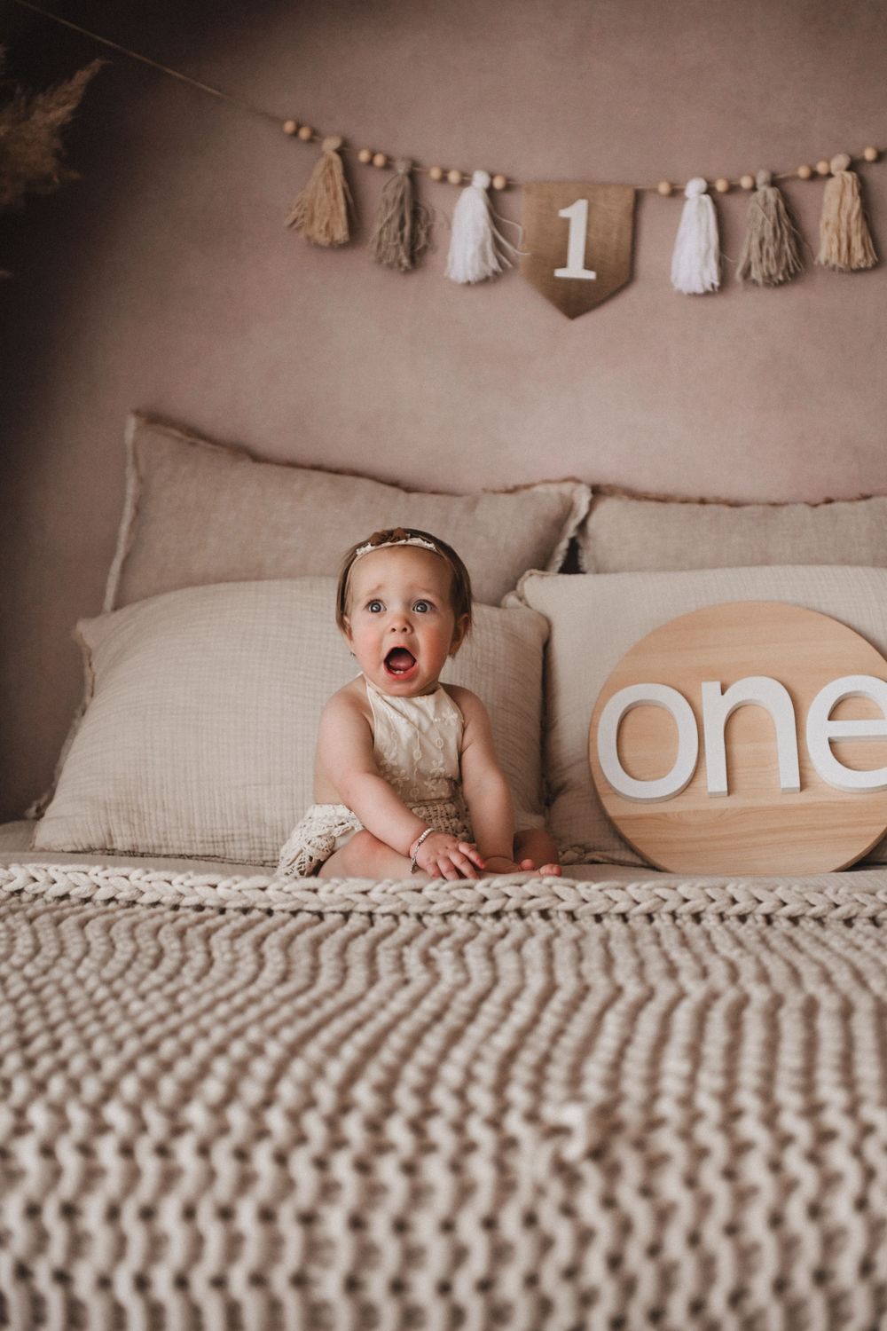 Cozy bed setting with knitted blanket and decorative ONE text display.