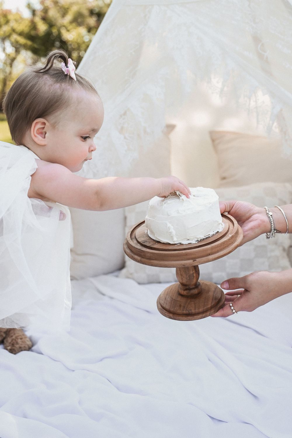 A series of photos showing hands reaching for a wooden cake stand with a birthday cake.
