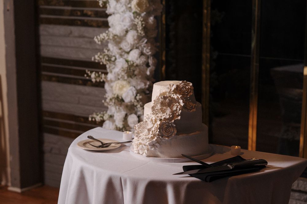 Elegant wedding table setting with white tablecloth and tall cascading floral arrangement in soft neutral tones.