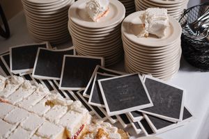 A collection of white ceramic plates and dishes arranged in a commercial kitchen setting with some remnants of food visible.