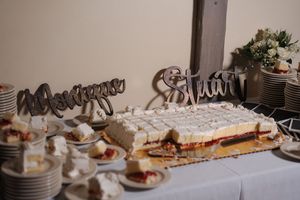 A dessert table with plates of pastries and a large decorated sheet cake at a wedding reception.