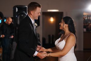 A couple shares a romantic dance together in a dimly lit venue during what appears to be a wedding reception.