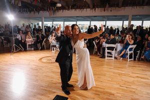 Couples elegantly dance across a polished wooden ballroom floor during a formal wedding reception event.
