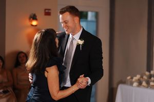 Two people share a dance together at an indoor event with soft lighting and tables visible in the background.