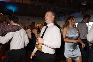 People dancing in formal attire at what appears to be a wedding reception or celebration event.