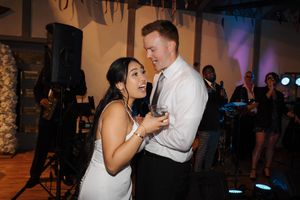 Wedding guests dance and mingle at an evening reception with colored lighting and decorative elements.