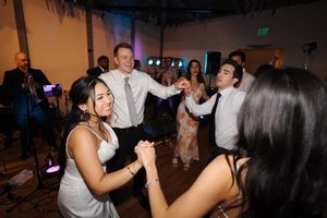 Guests dance and mingle during a lively reception party in a dimly lit venue space.