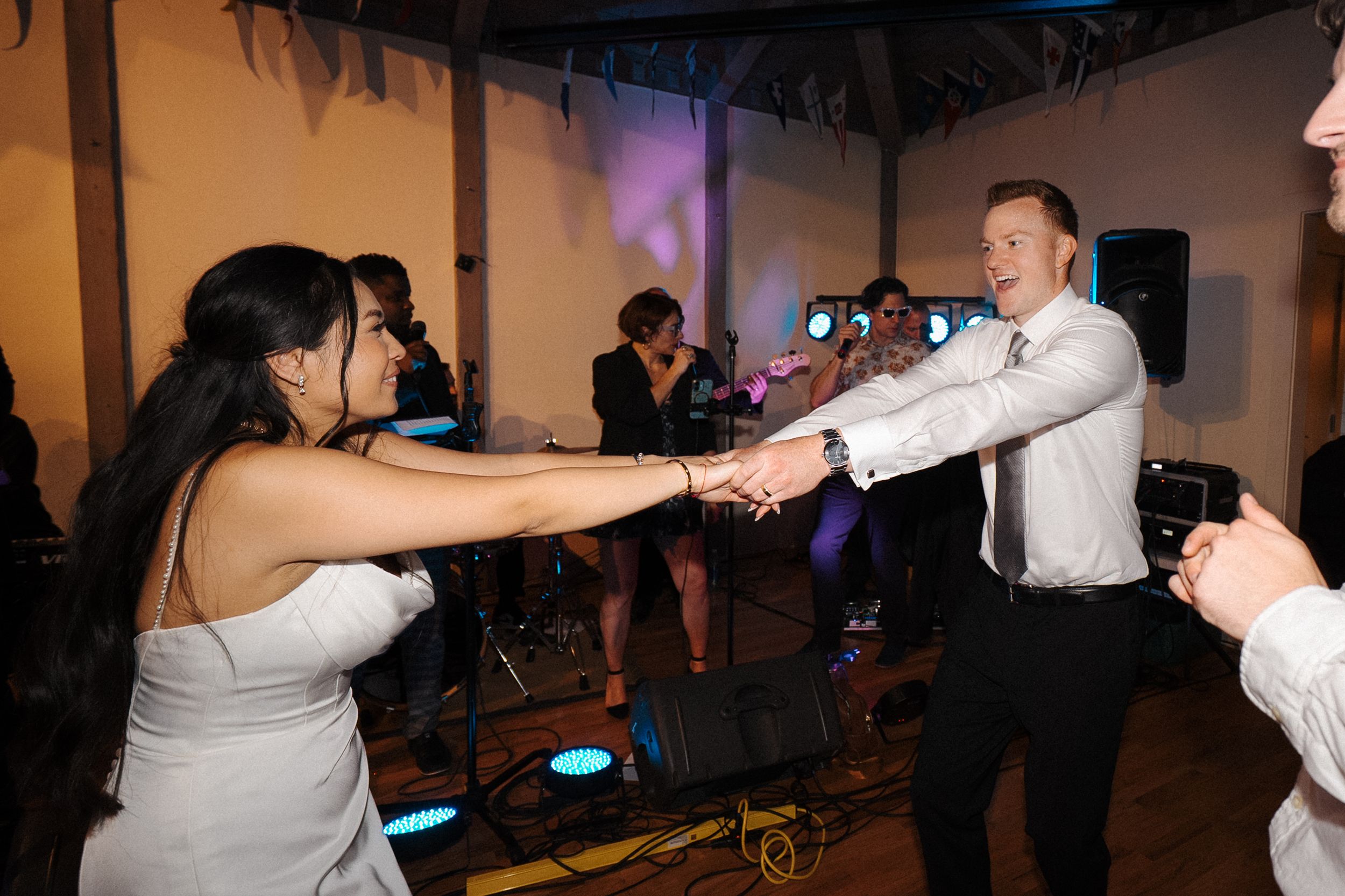 People dance at a celebration in a dimly lit reception hall.