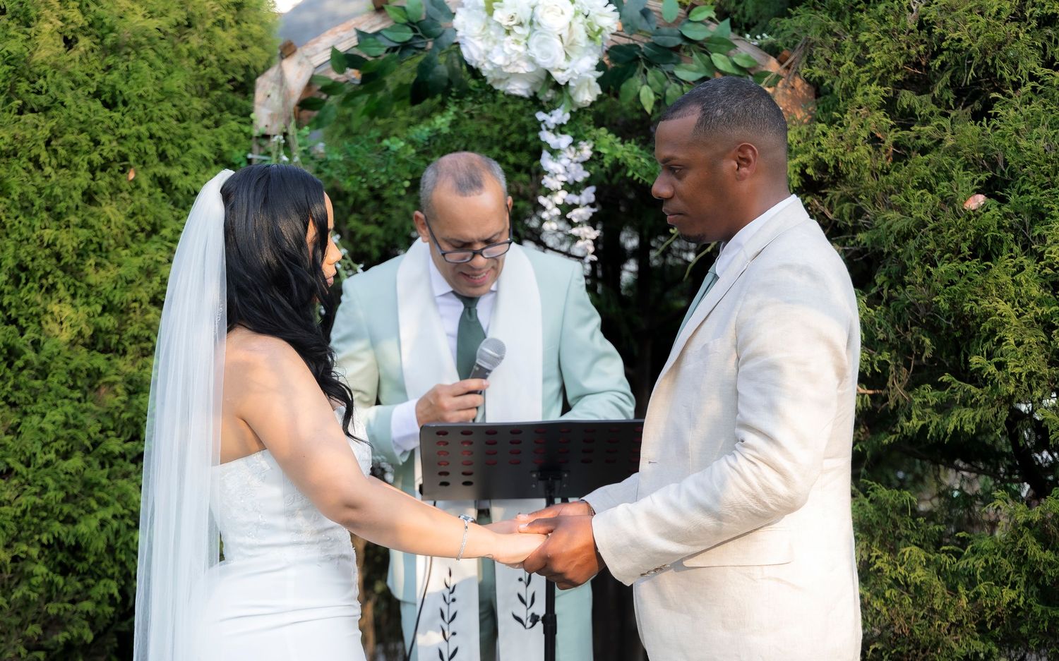 A romantic kiss between a couple at their outdoor wedding surrounded by lush greenery.