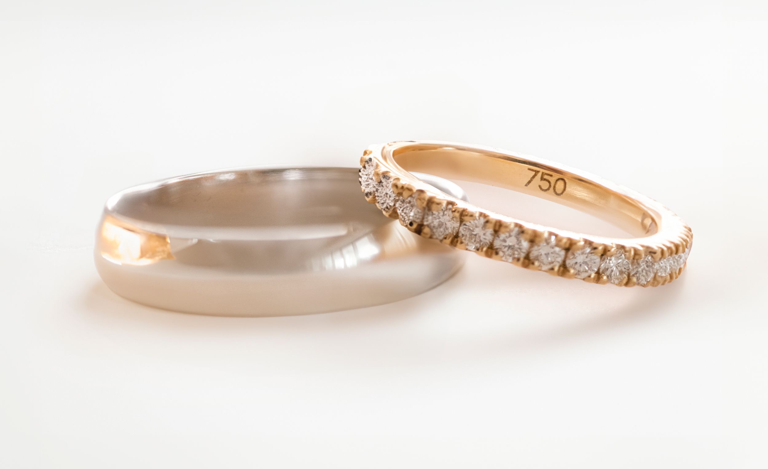 Three delicate rose gold rings with diamonds set in an eternity band style on a white background.