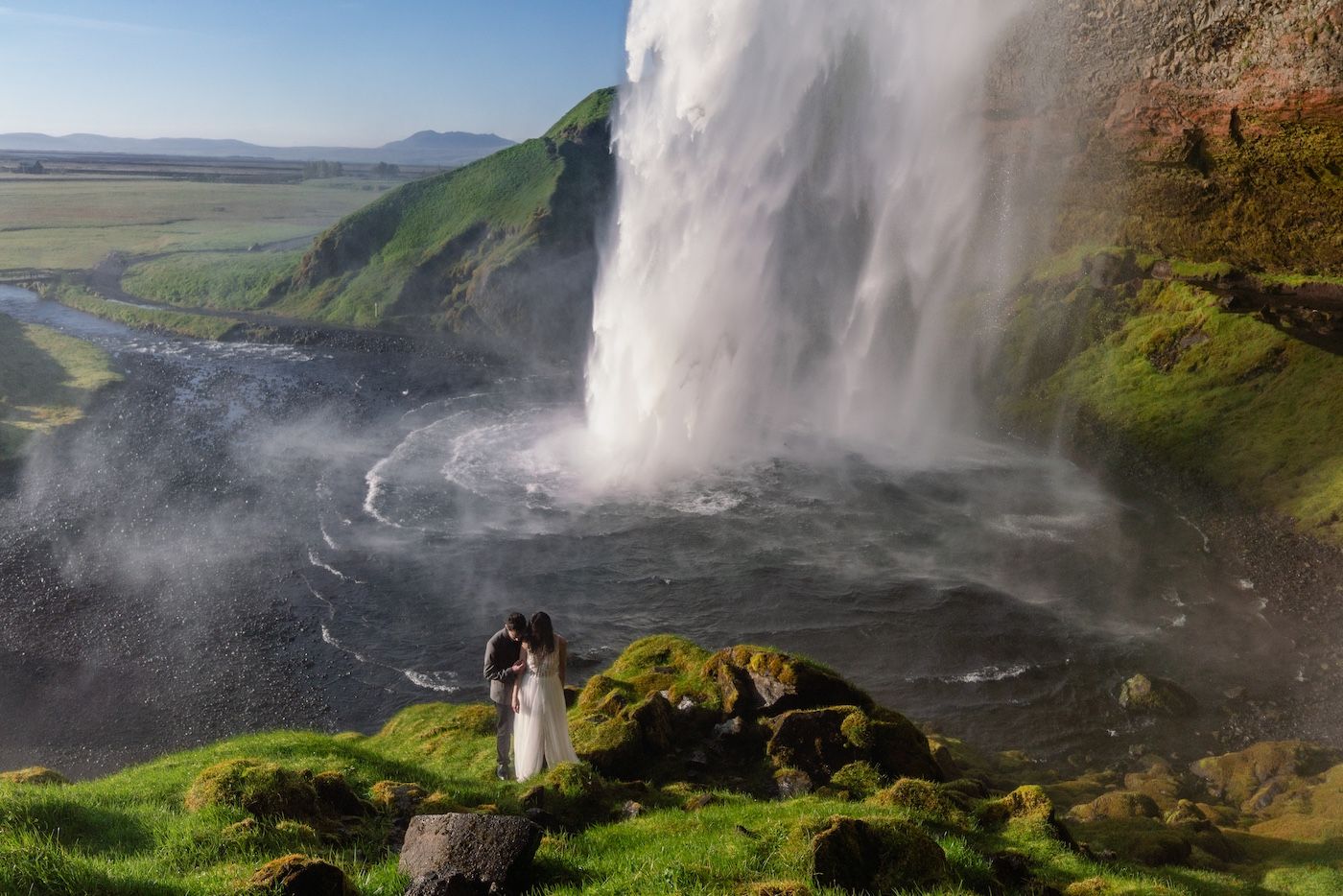 Couple hugging in front of seljalandsfoss.