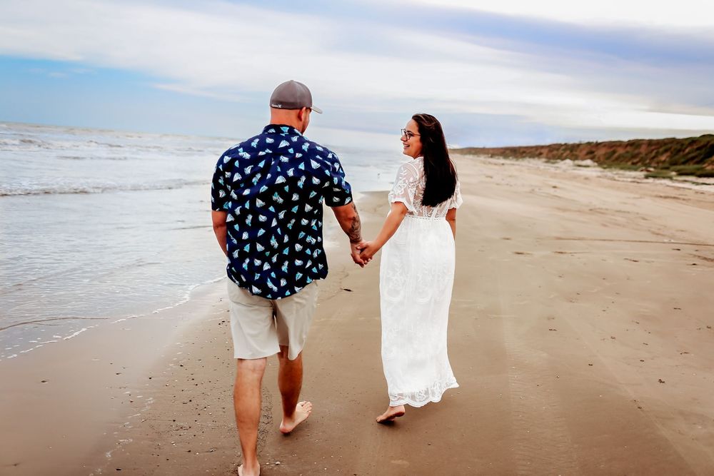 Husband and wife on the beach holding hands for maternity session