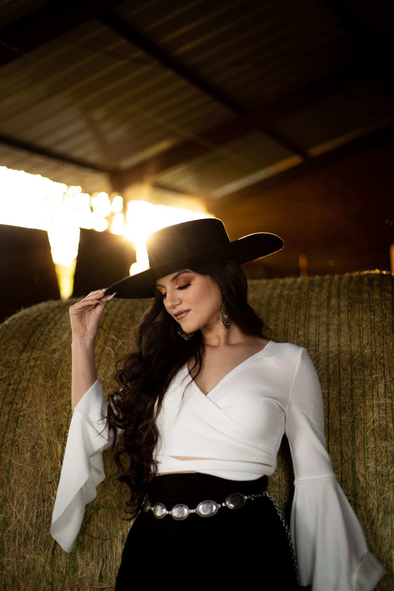 Dramatic portrait with sunlit ceiling beams and rustic barn interior.