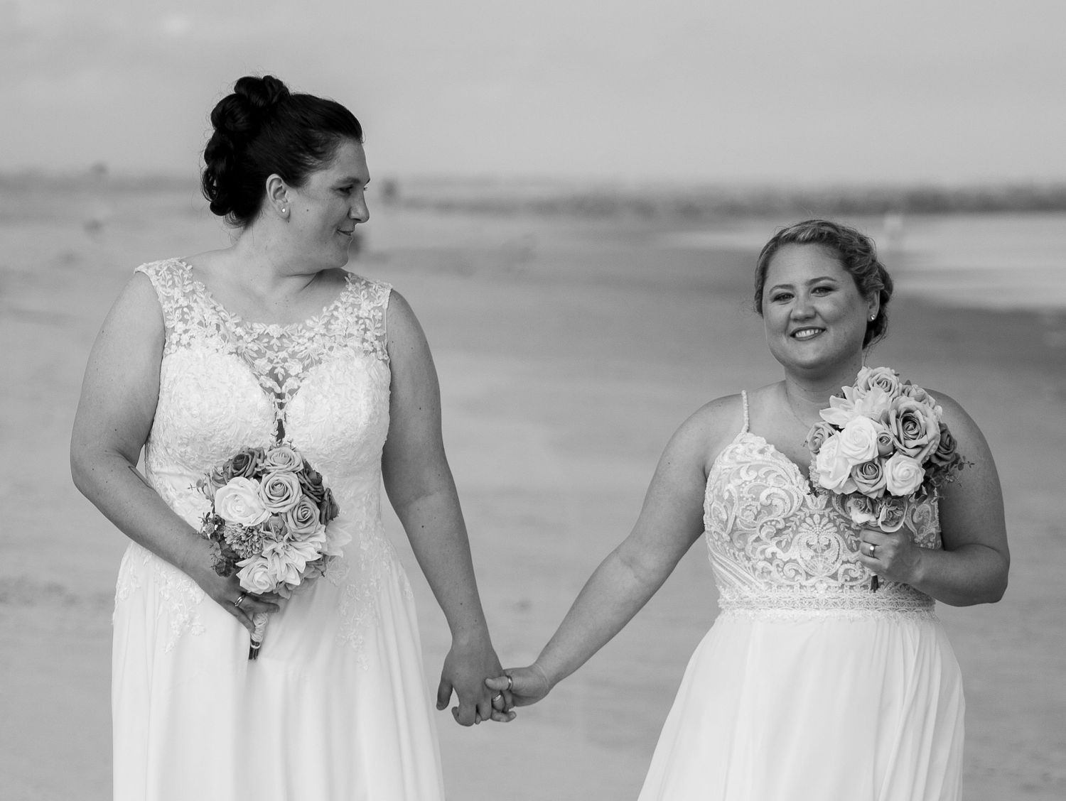 A dreamy black and white photograph captures intimate wedding moments along the shoreline.