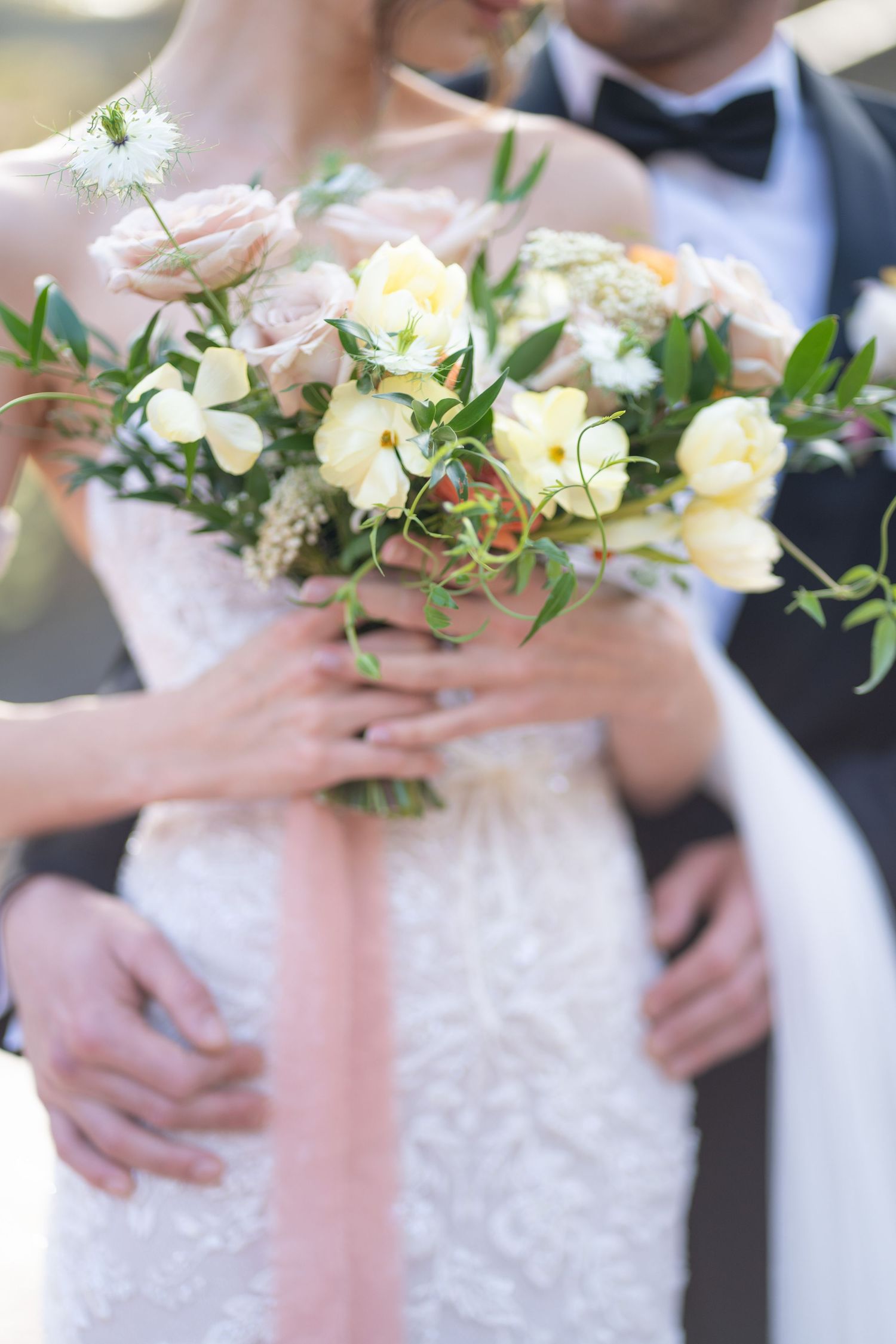 Close-up details of a bridal bouquet featuring cream roses and delicate greenery.