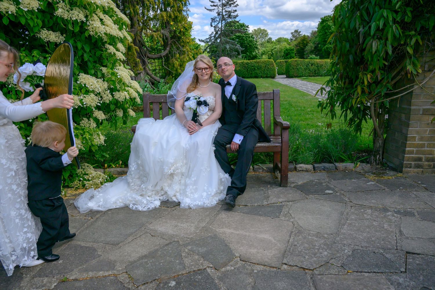 Seven wedding photos side by side showing a scenic garden setting with stone walls, flowering trees and a pathway.