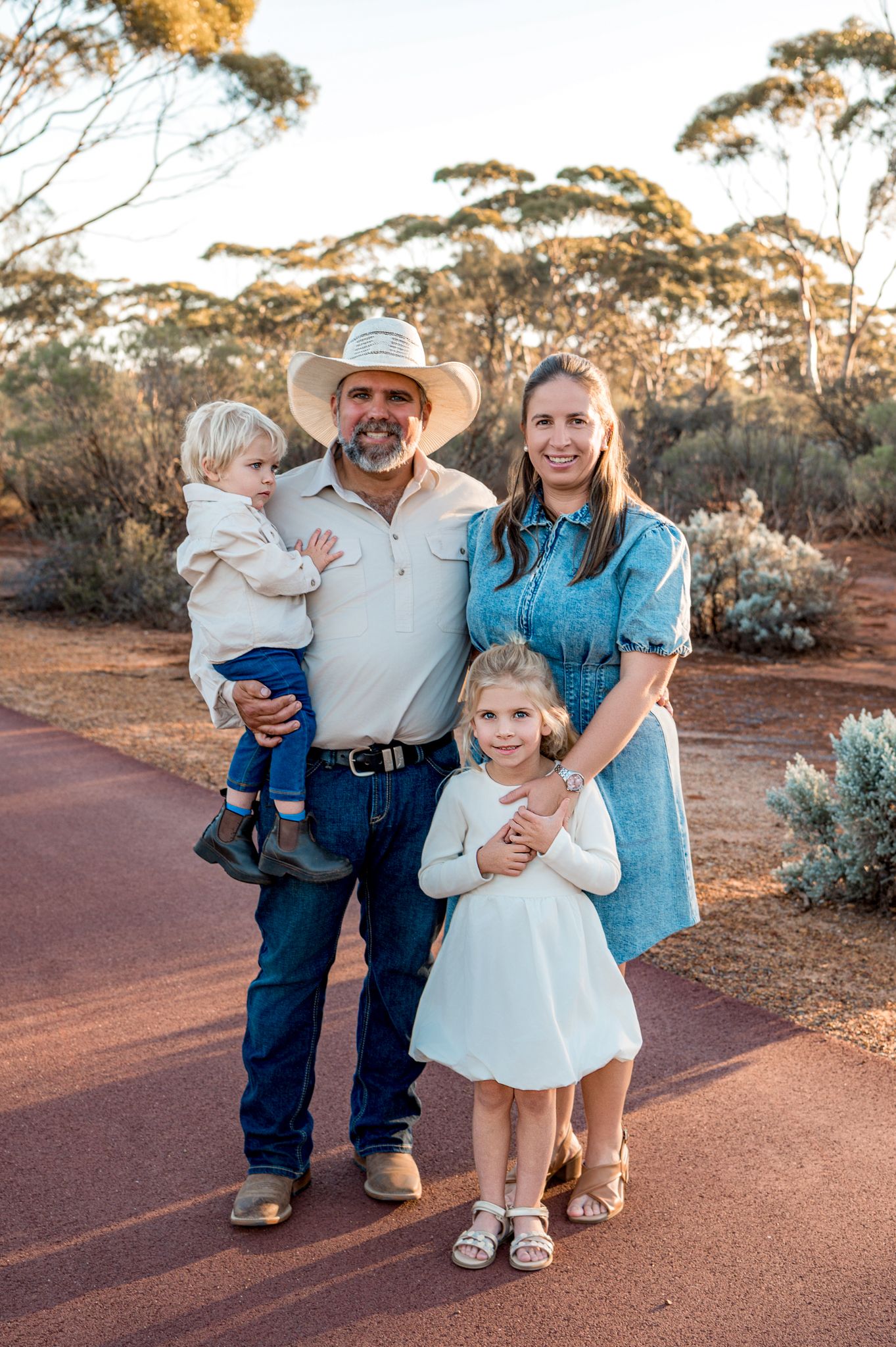 Children stroll along a rustic path at sunset during a golden hour outdoor family photo session.