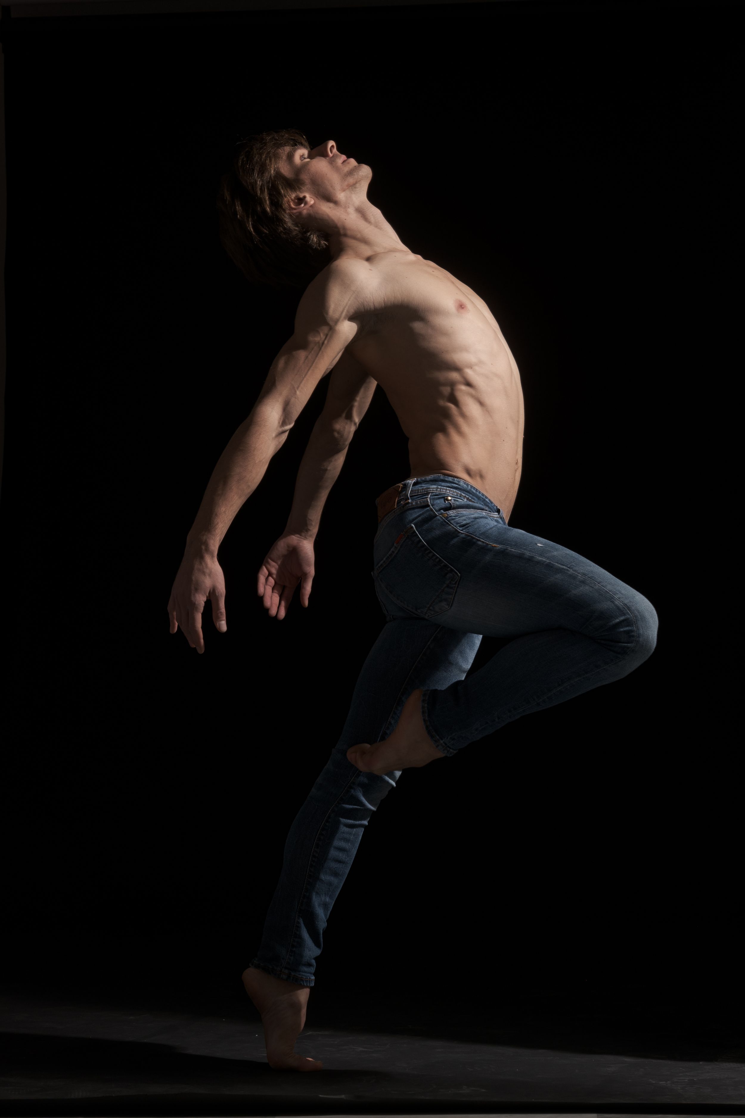 Dynamic dance sequence showing athletic movement in low light against black background.