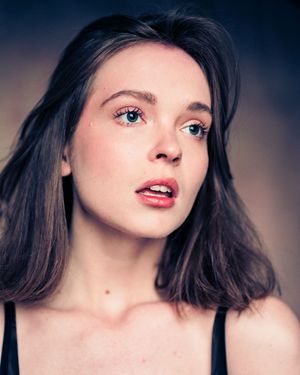Close up beauty portrait with soft lighting and natural makeup against blurred background.