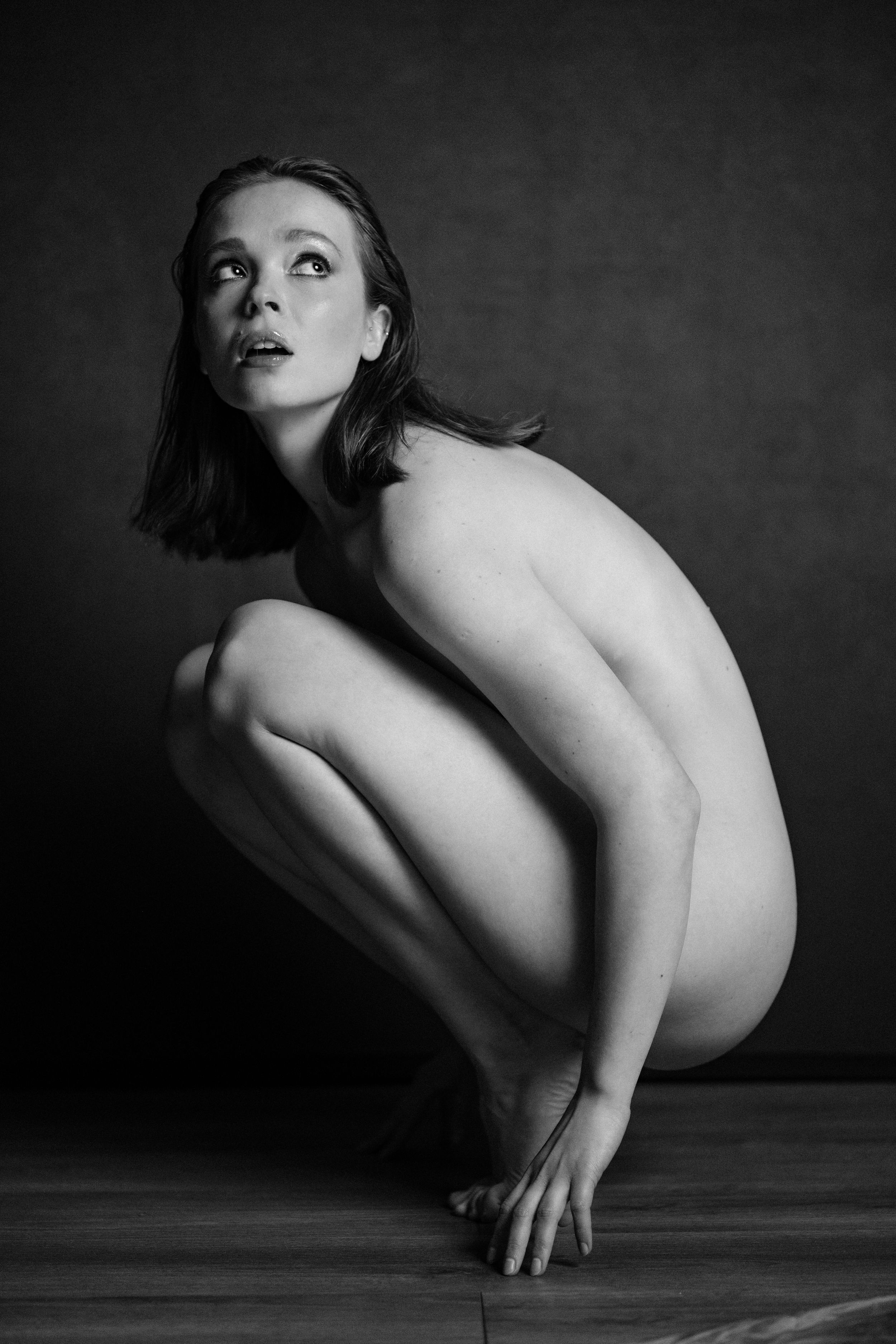 Artistic black and white nude study showing curved forms and shadows.