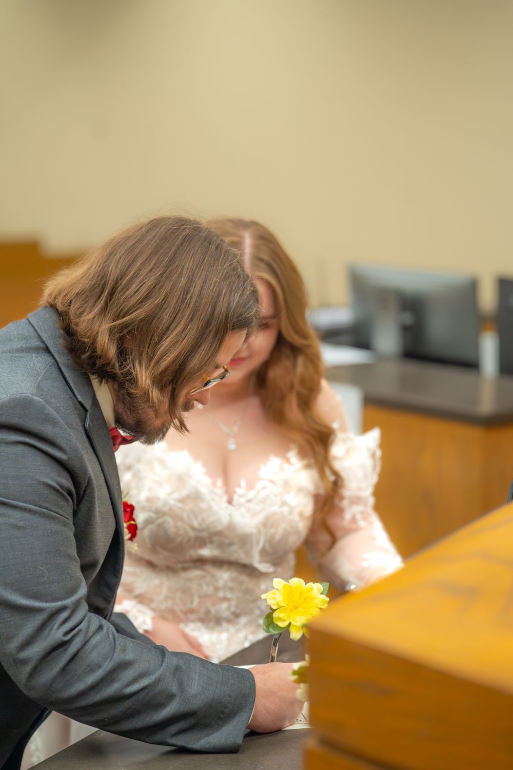 A yellow flower rests on a wooden table during a courthouse wedding ceremony.