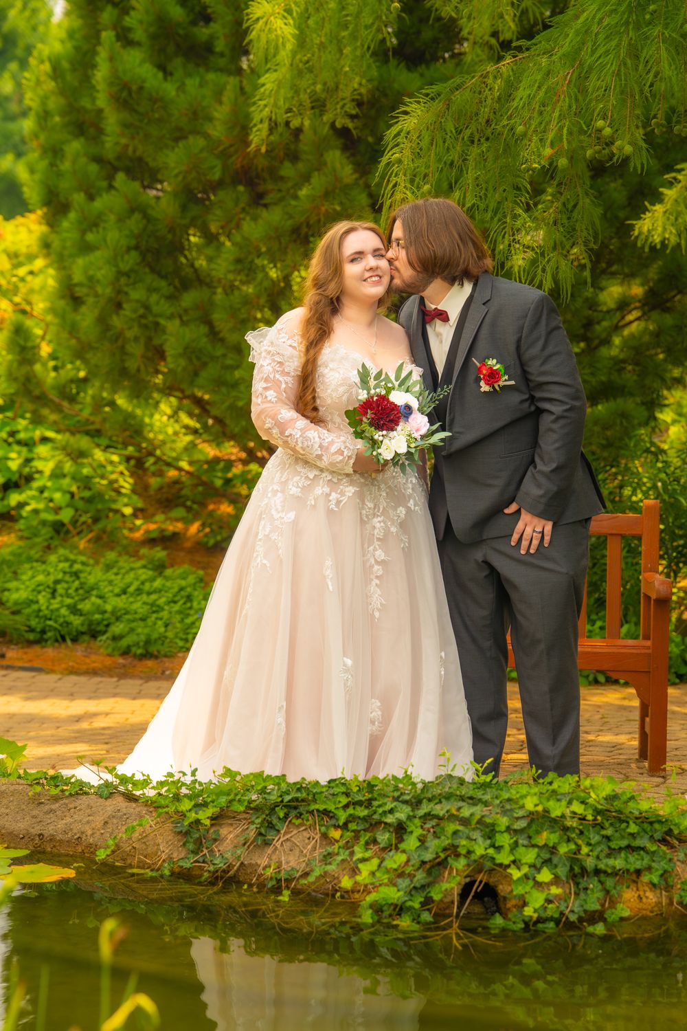 A romantic wedding photo series by a tranquil pond featuring a couple in a lush garden setting with greenery.