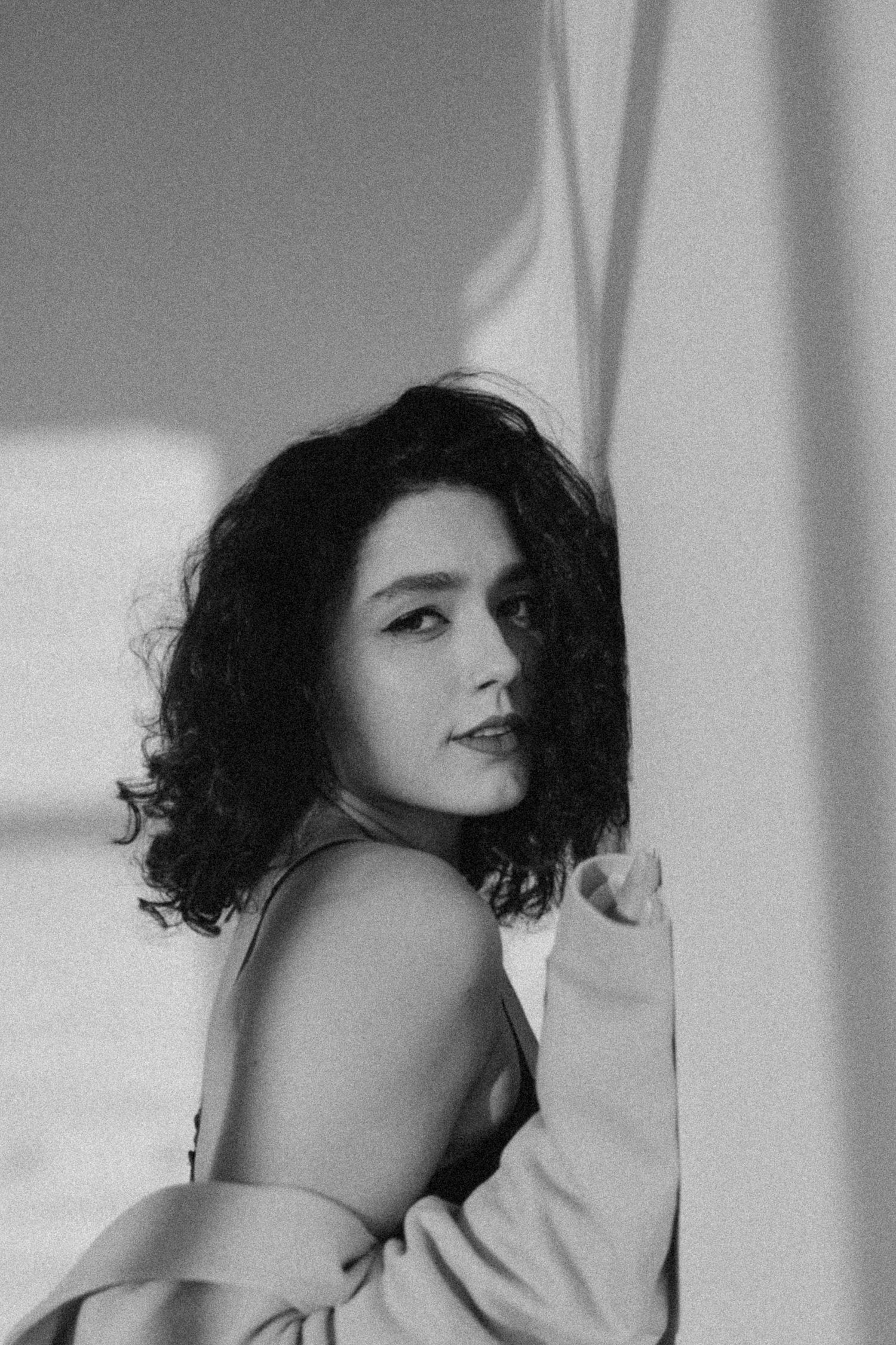 Black and white portraits with curly hair and dramatic window light casting shadows.