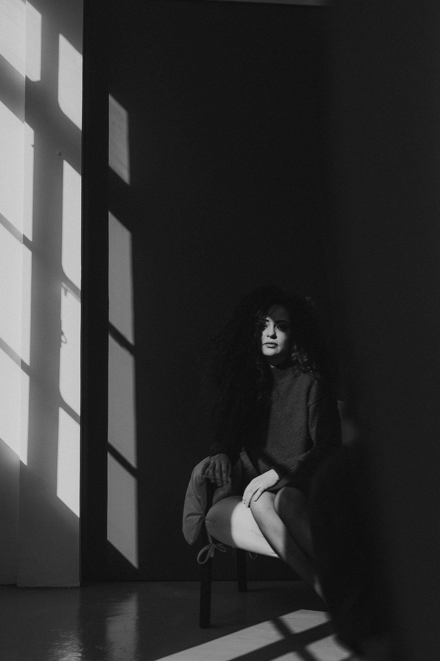 Dramatic black and white photos with window light creating geometric shadows on wall.