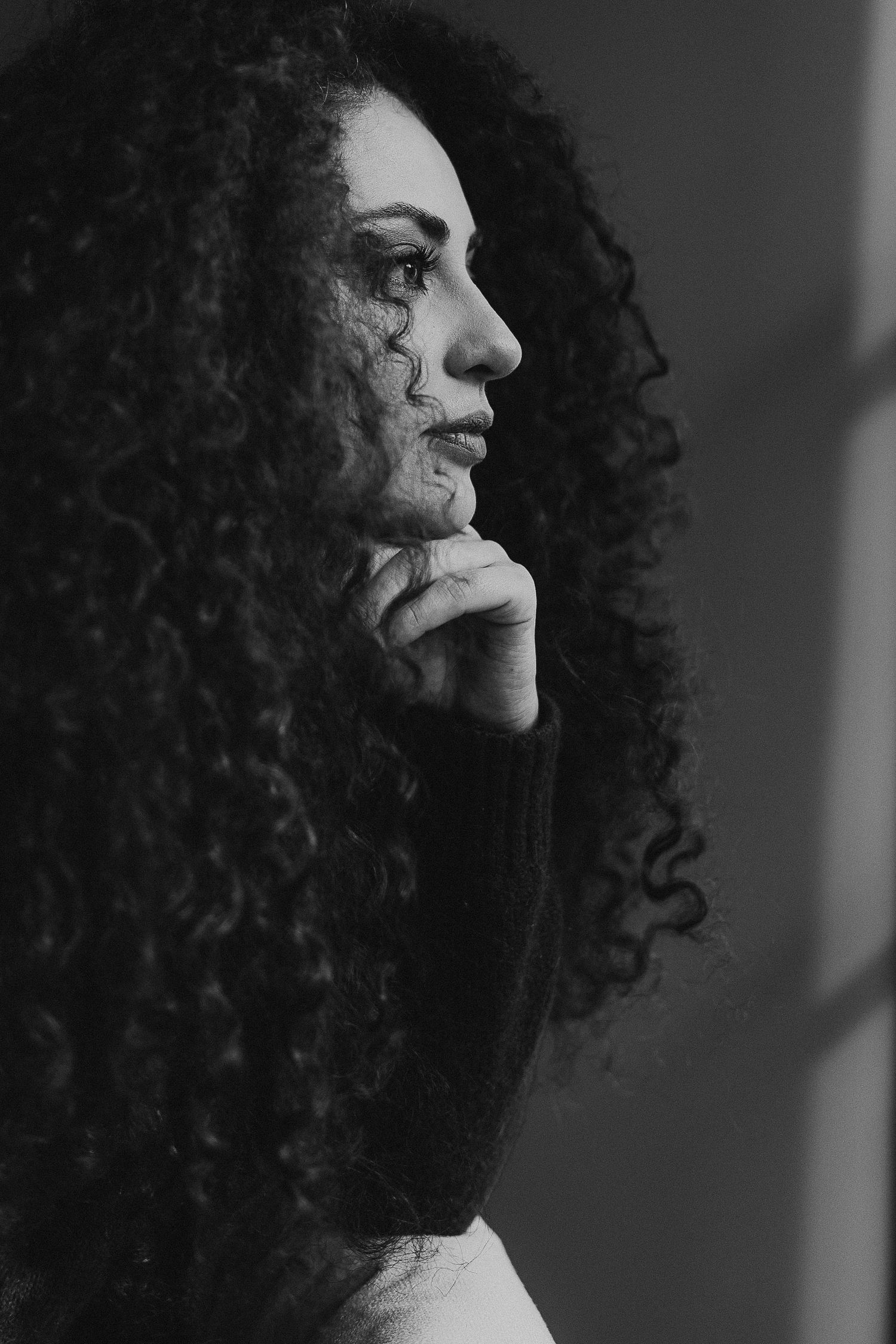 Black and white profile portraits showing natural curly hair texture with moody lighting.