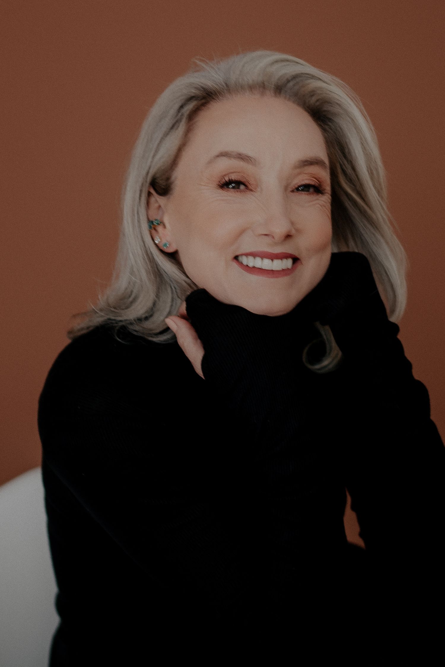 Studio portrait with warm lighting and black turtleneck sweater.