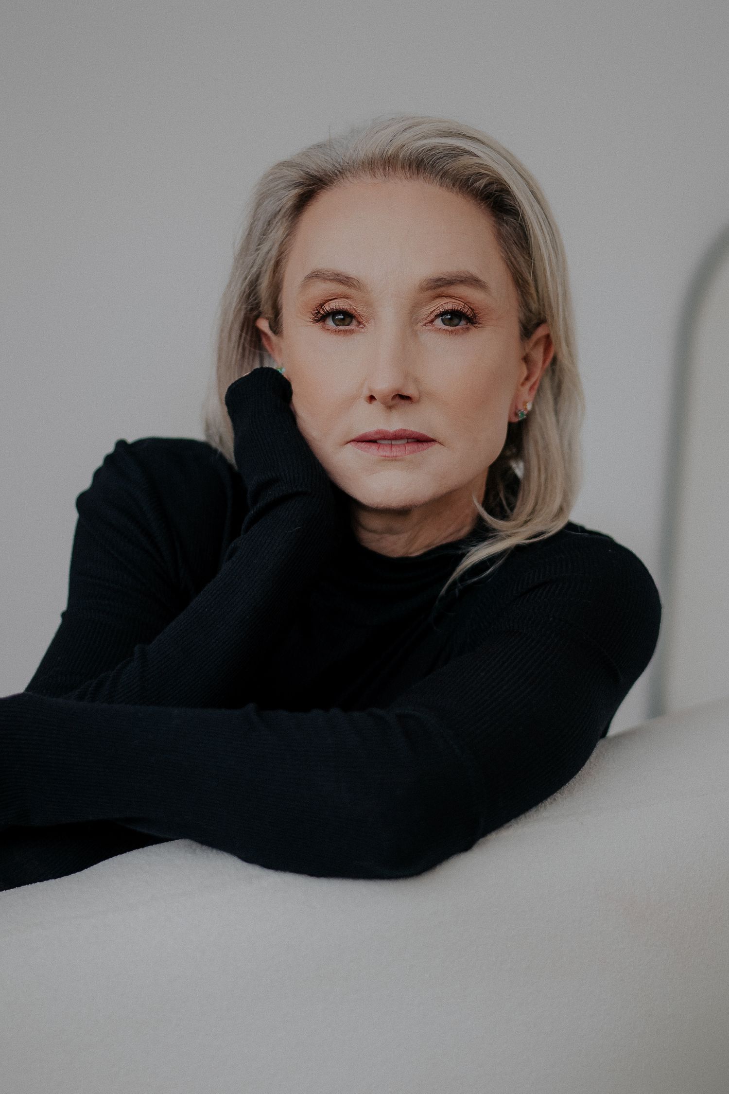 Elegant studio portrait in black sweater against neutral background.