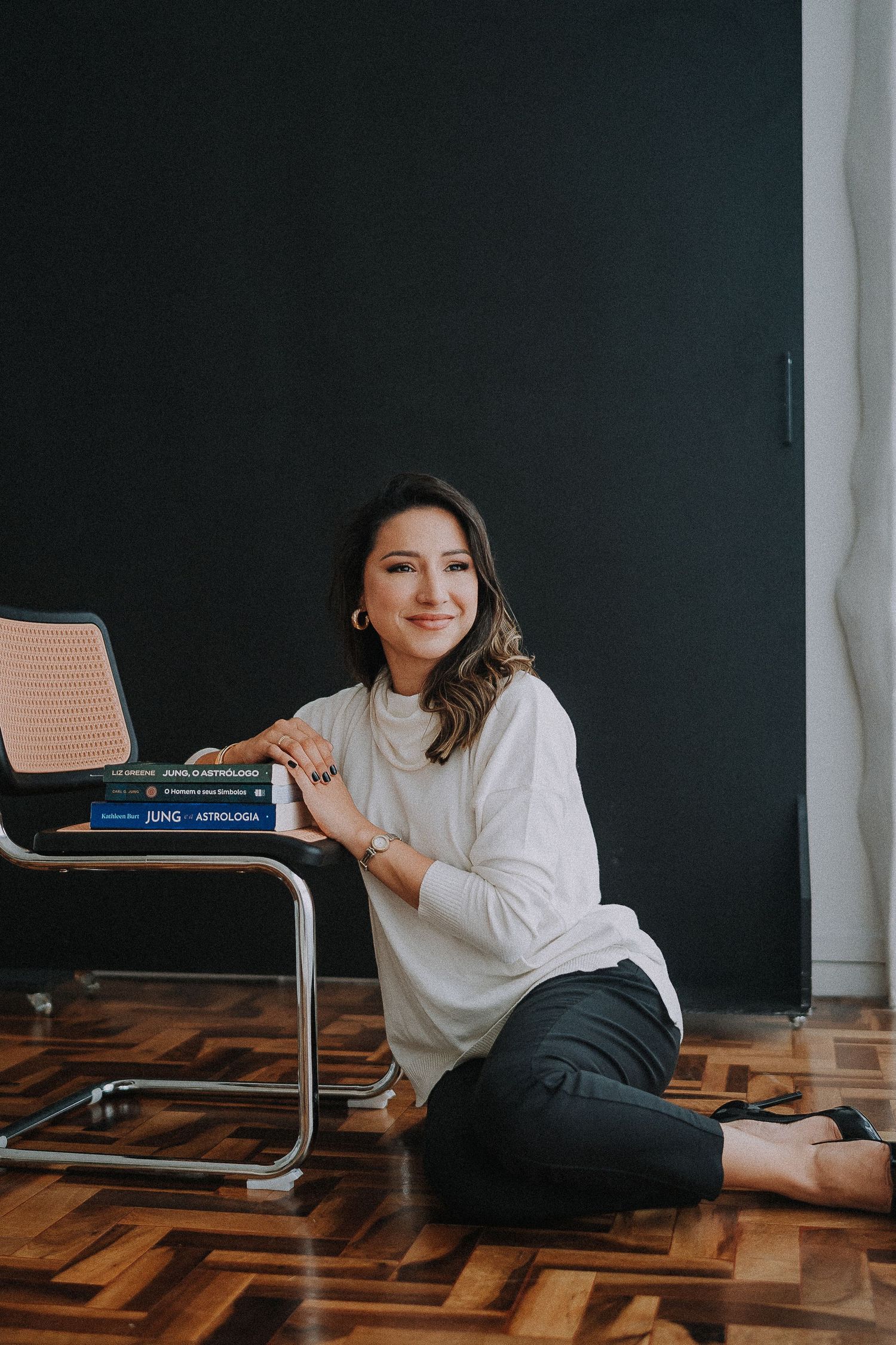 Relaxed lifestyle portrait on wooden floor with modern chair in studio setting.