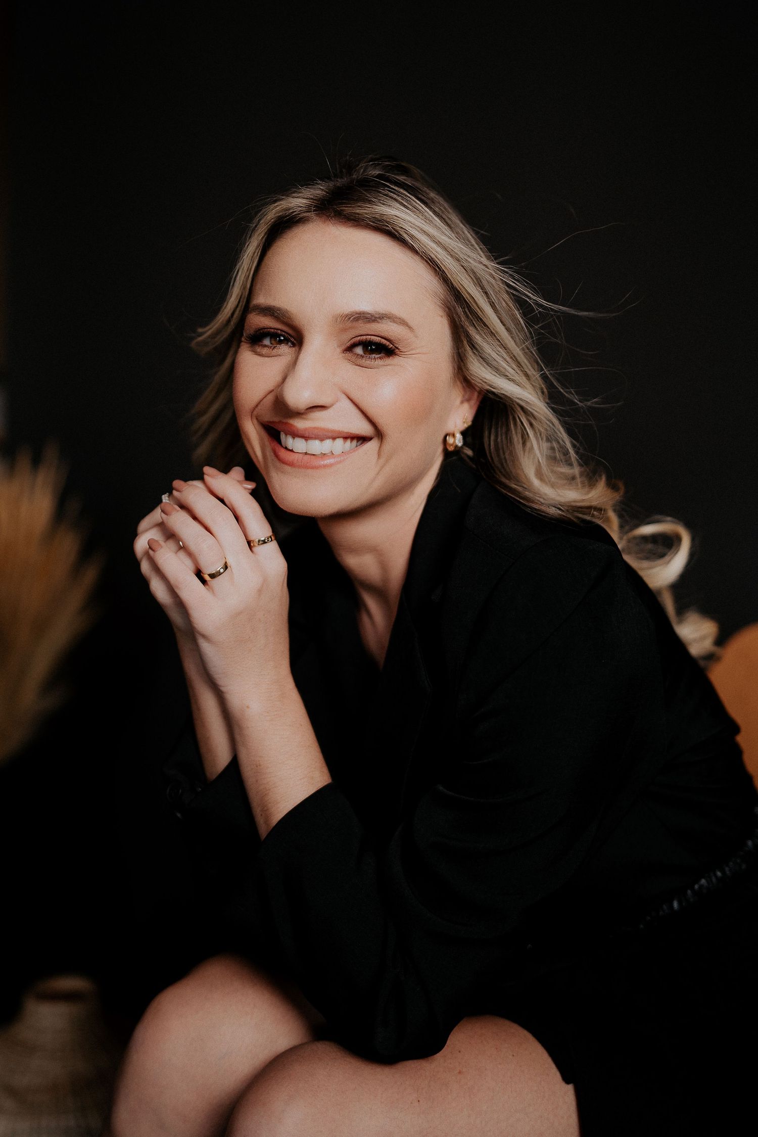 Elegant studio portrait with black sweater and natural makeup against dark backdrop.