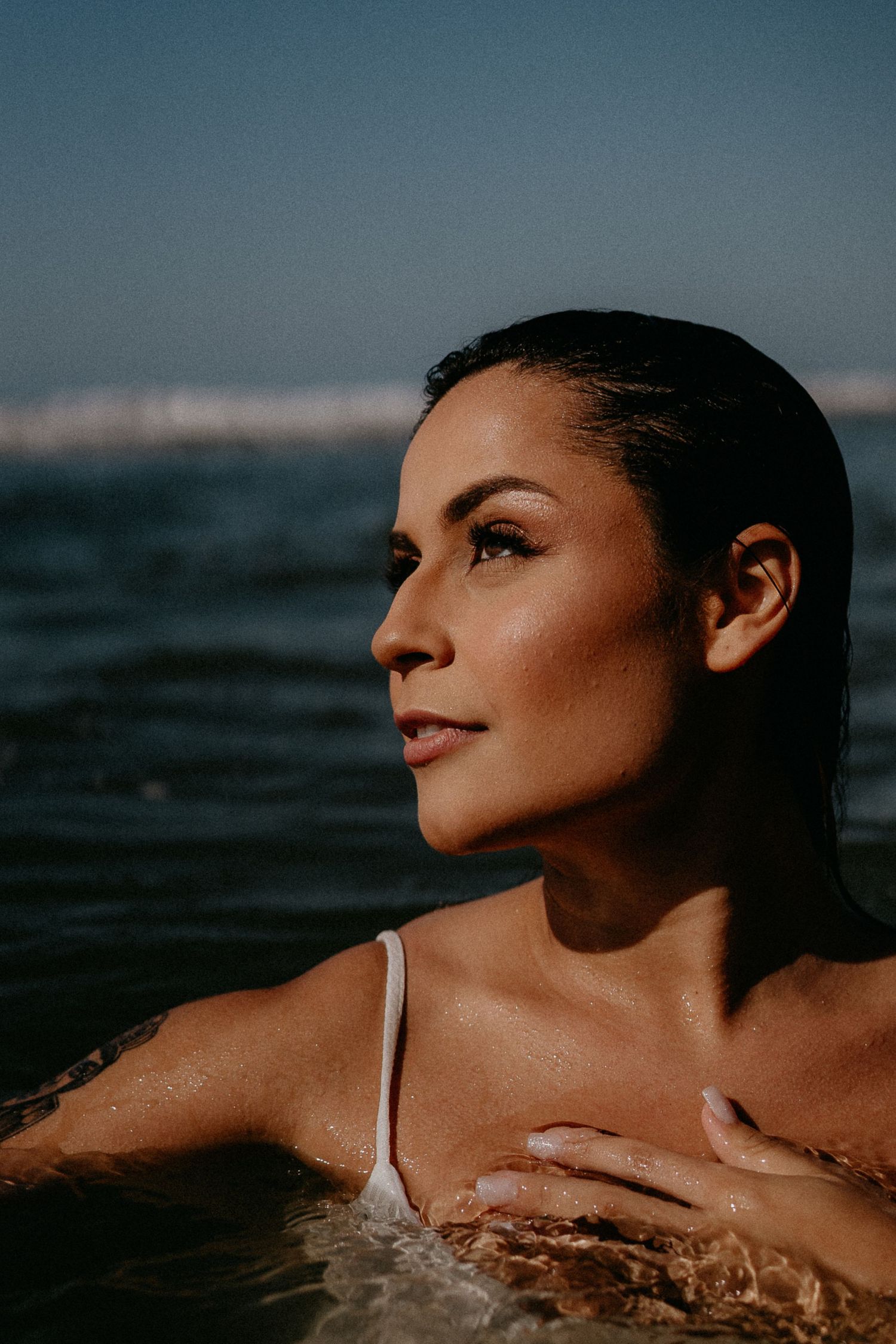 Artistic beach portraits in water during sunset with dramatic lighting.