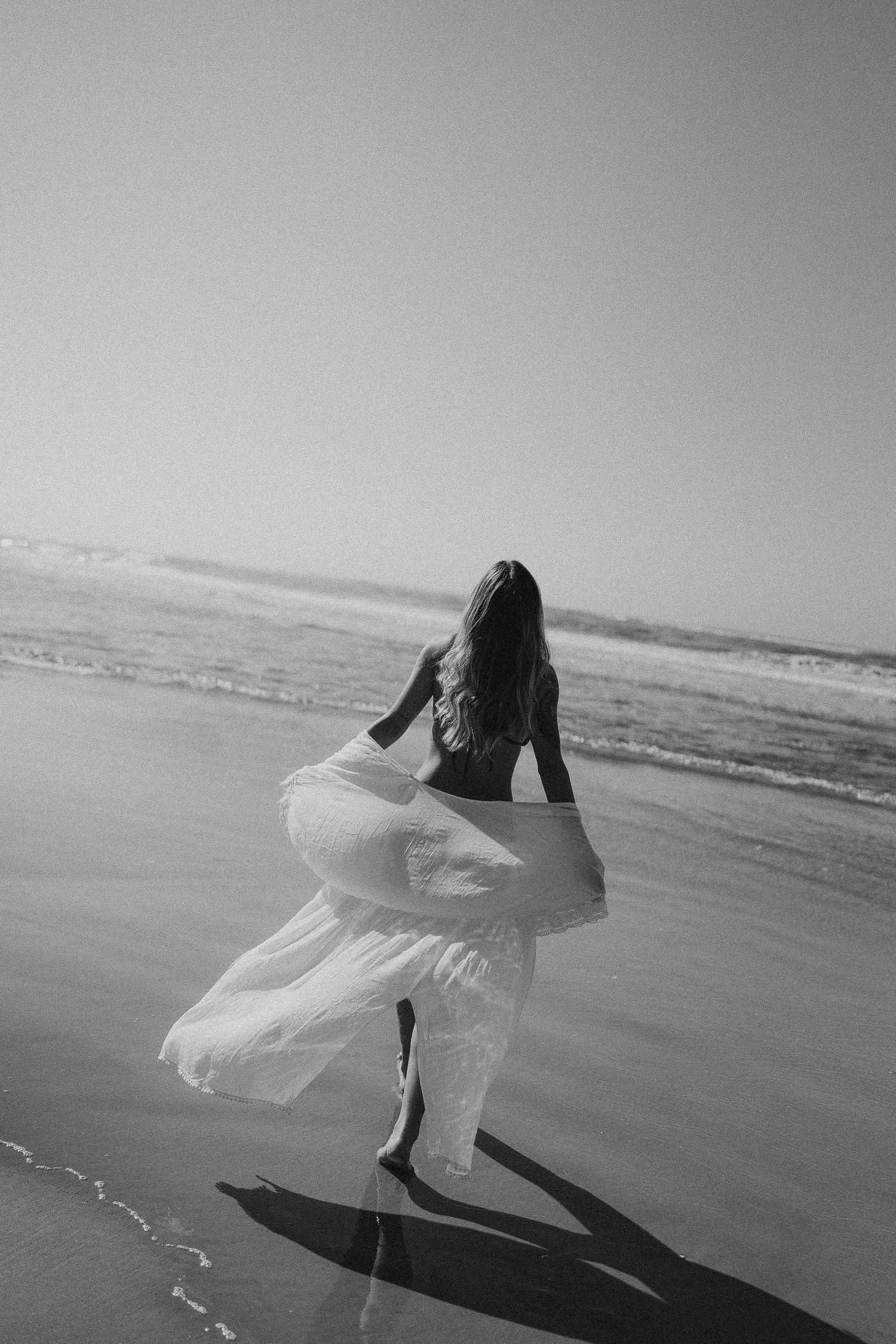 Ethereal black and white sequence of flowing white dress movement on beach.
