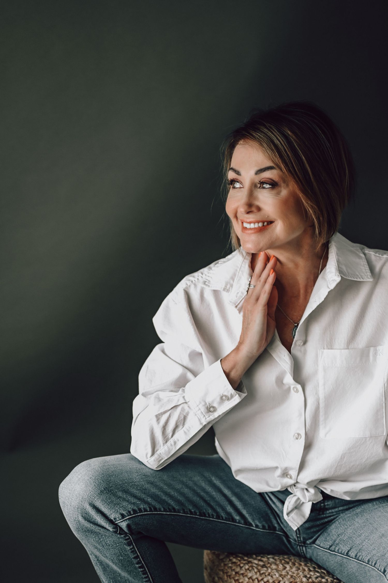 Portrait series of person in white button-down shirt and jeans against moody green background.