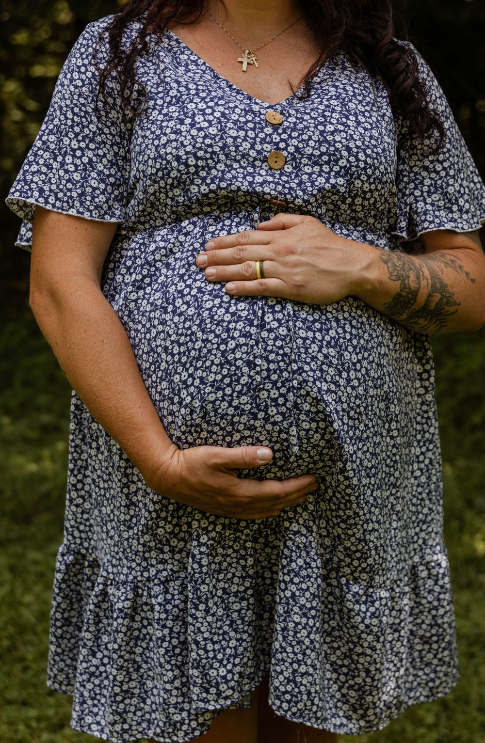 A series of photos showing a pregnant belly in a navy floral print dress against a dark outdoor background.