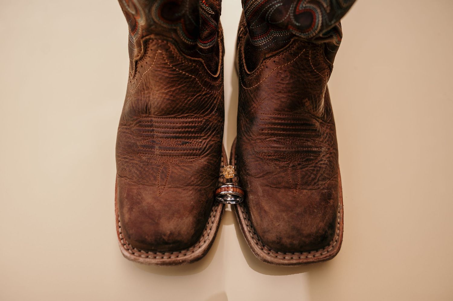 Closeup views of traditional brown leather cowboy boots showing details of stitching and weathered patina.