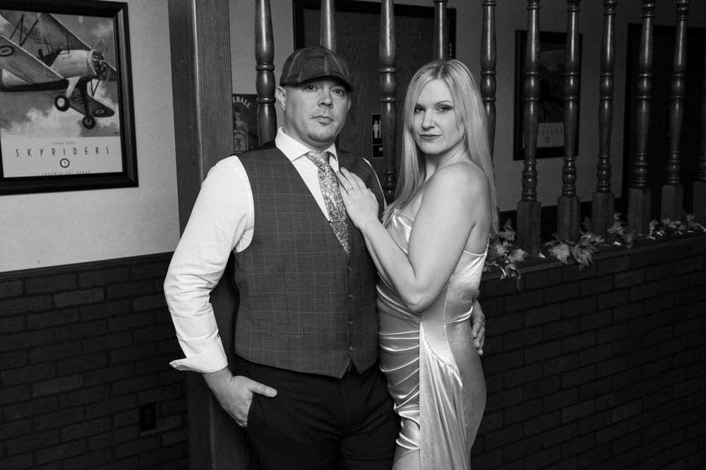 Two people stand close together in formal attire at a special event in a dimly lit venue.
