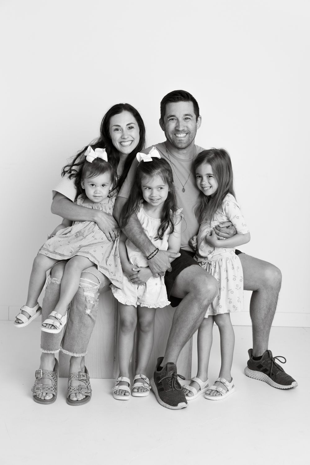 Black and white portrait series showing a family sitting and posing together with matching outfits and shoes.