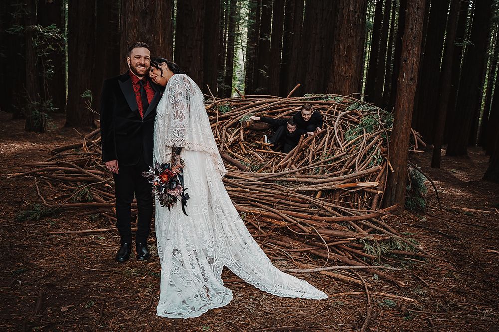 Newlyweds share an intimate moment amidst ancient redwood trees with a long flowing lace wedding dress.