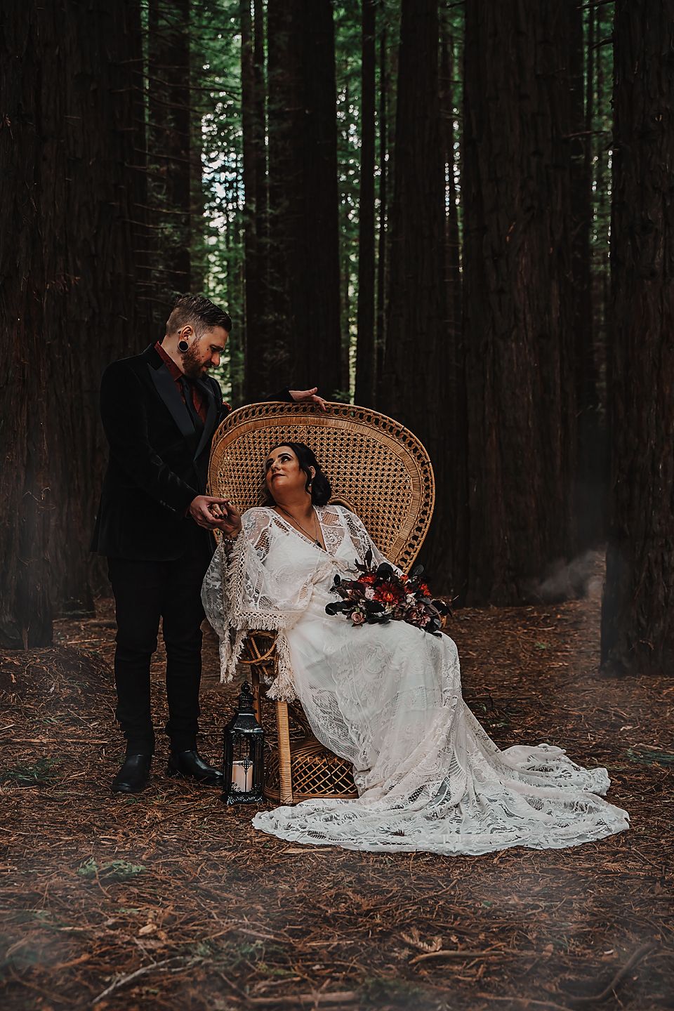 A whimsical wedding photo series in a forest setting with a bride in a lace gown seated on a peacock chair.
