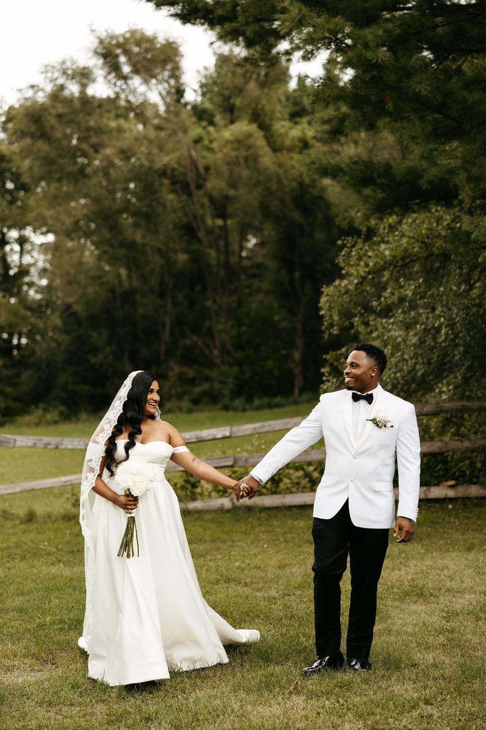 Wedding couple dances and twirls playfully on a grassy hillside during their outdoor photo session.