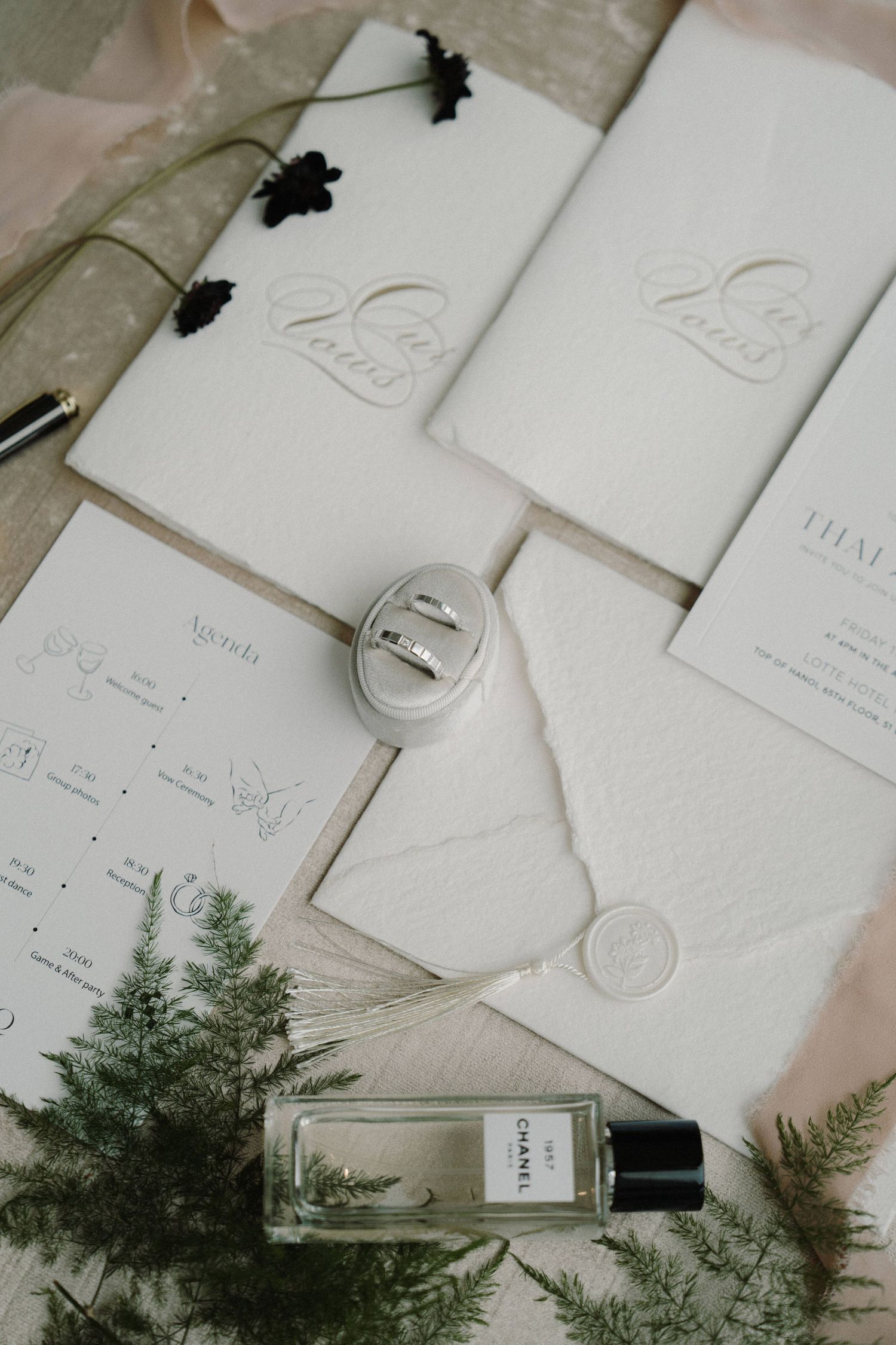 Wedding invitation stationery with delicate typography and evergreen sprigs on a light background.