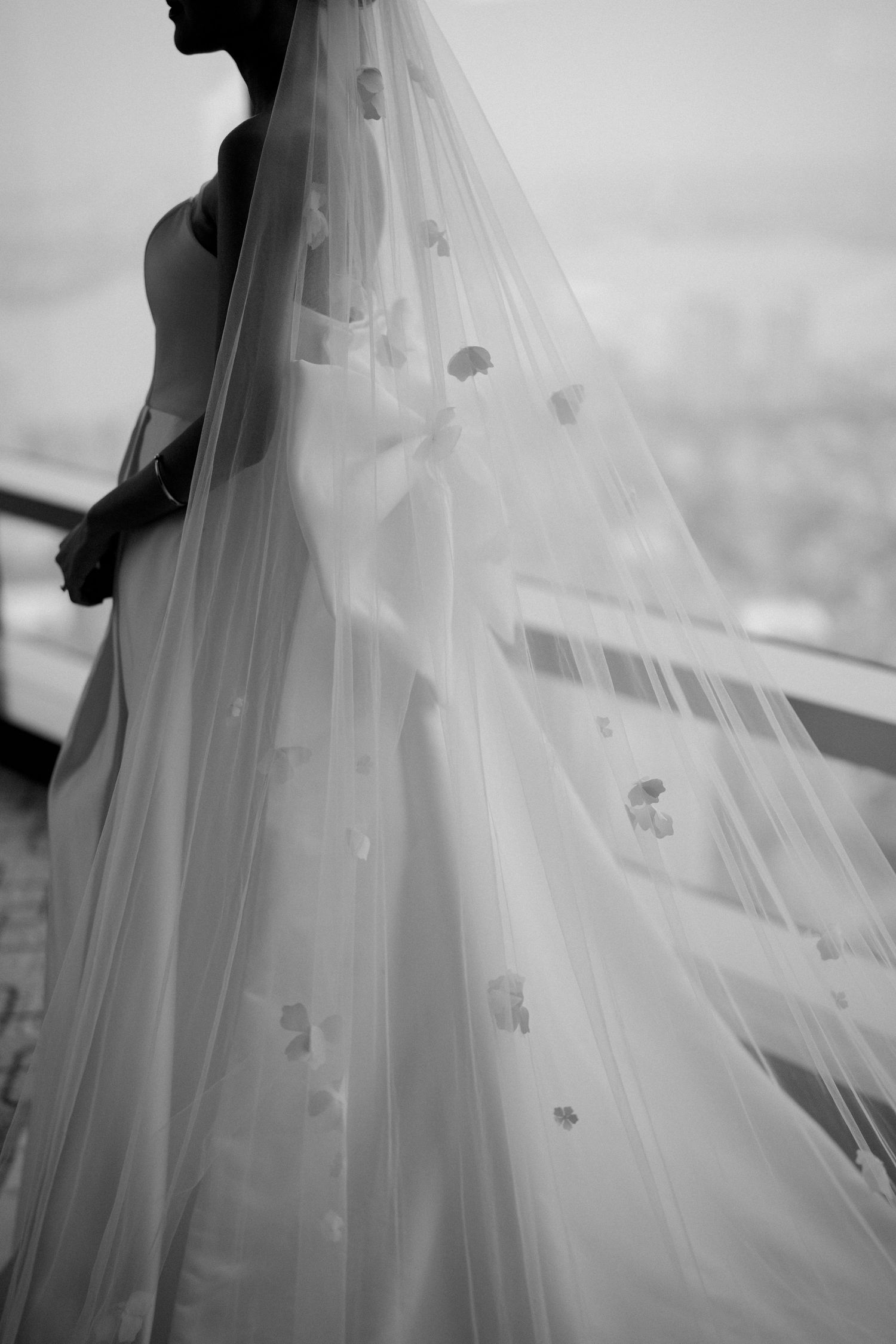 Flowing white wedding veil with delicate floral details captured in black and white.