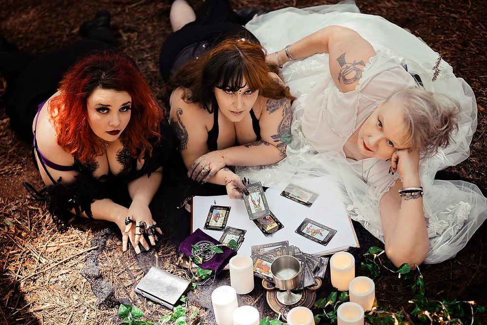 People gather on forest ground with candles and frames for an enchanting woodland photoshoot.