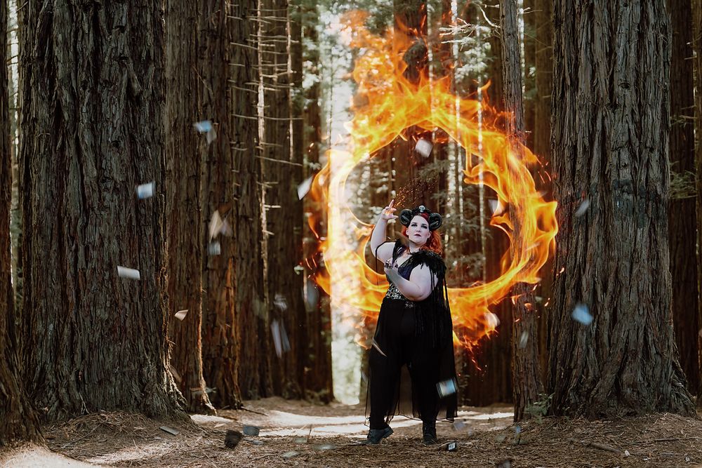 Fantasy-themed photo session in a forest with fire effects and tall tree trunks.