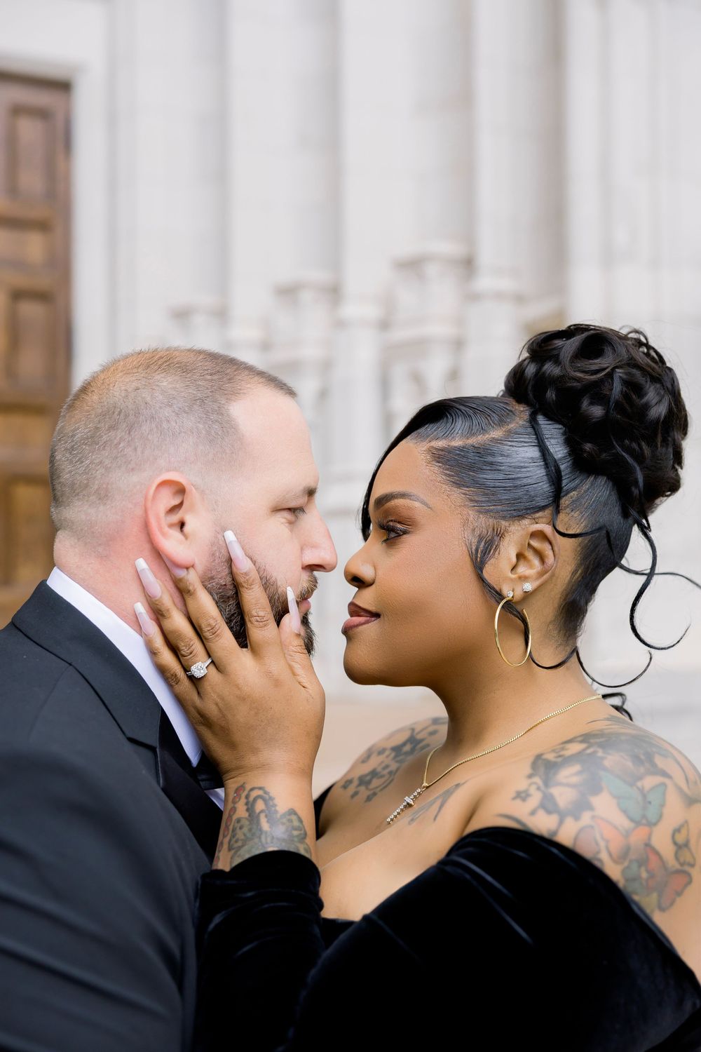 Intimate close-up portrait of couple with ornate church architecture in background.