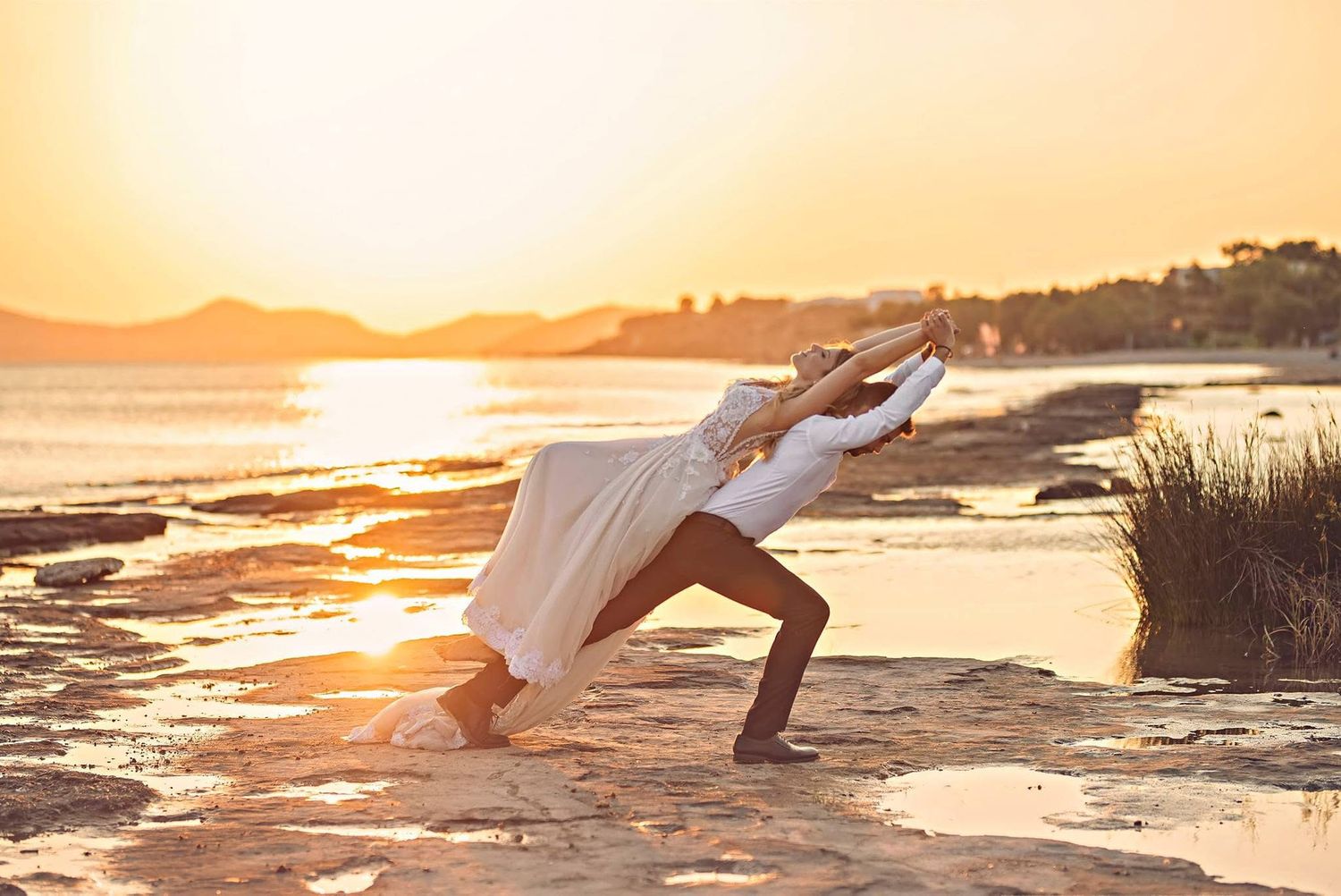 Silhouette of person stretching in yoga pose at sunset on cliff edge overlooking ocean.